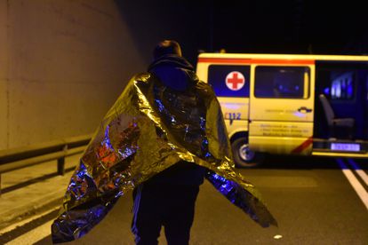 Un herido cubierto con una manta térmica se desplaza hacia una de las ambulancias desplegadas en el lugar del siniestro.