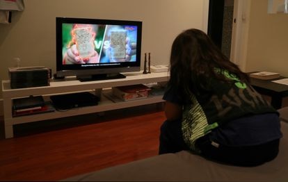 Un menor ve en la televisión publicidad de galletas.