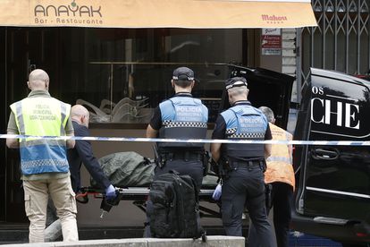 Sanitarios y policías trasladan el cadáver de una mujer asesinada en Pamplona por su pareja el sábado.