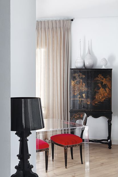 Detalle del comedor, con un armarito chino comprado en el Rastro madrileño reconvertido en mueble bar. Sobre él, una piña blanca de cerámica siciliana que es un icono de buena suerte en Italia. La mesa y la lámpara son de Kartell.