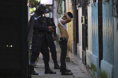 A police officer searches a man in Soyapango, El Salvador
