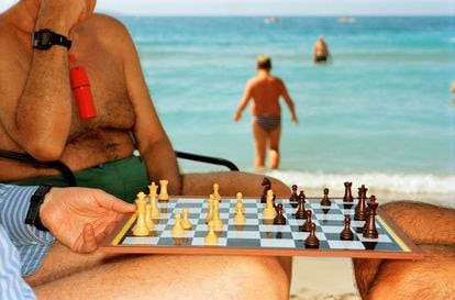 Tres personas con una tabla de ajedrez en una playa de Benidorm, en 1997.