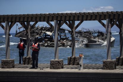 Guardacostas en el puerto de Lahaina ante un barco calcinado, este viernes en la isla de Maui (Hawái).
