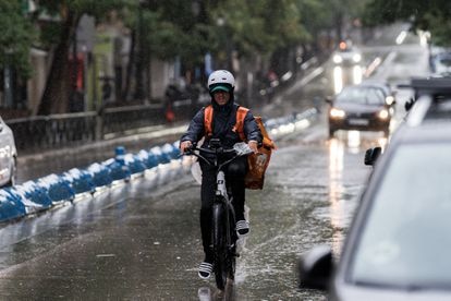 Un repartidor trabaja bajo la tormenta, este domingo en Madrid.