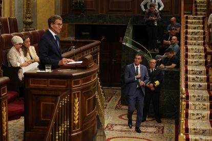 El presidente en funciones, Pedro Sánchez, entra en el hemiciclo, mientras el candidato popular, Alberto Núñez Feijóo, interviene desde la tribuna de oradores.