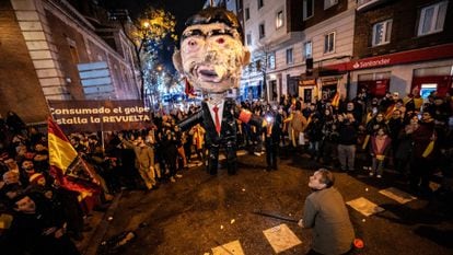 Un hombre se dispone a apalear un muñeco con la figura de Pedro Sánchez en la protesta cerca de la calle de Ferraz en Madrid, en Nochevieja.