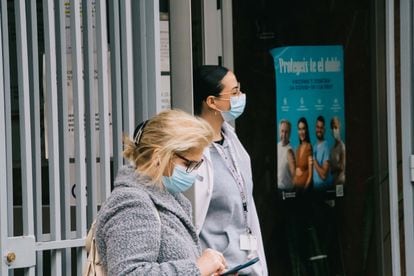 Una mujer y una sanitaria con mascarilla, en la puerta de un centro de salud de Barcelona, este viernes.