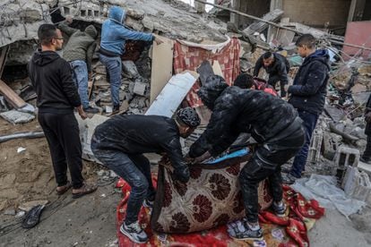 Varias personas buscan supervivientes entre los escombros de un edificio colapsado tras los ataques israelíes sobre Rafah, este lunes.
