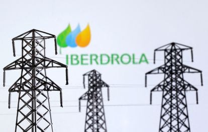 Miniaturas de torres eléctricas, con el logo de Iberdrola al fondo.