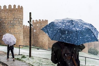 Dos personas pasean junto a la muralla de Ávila este viernes, bajo la nieve.