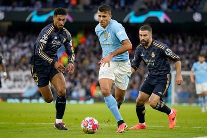 Rodri conduce el balón entre Bellingham y Carvajal.