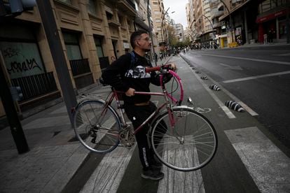 Un ciclista carga con su bicicleta por una avería en el carril bici de Gran Vía, este lunes en Murcia.