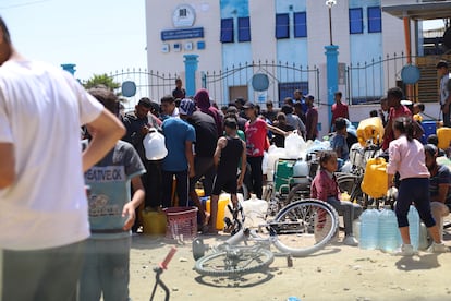 Refugiados palestinos esperan para coger agua y comida en Jan Yunis tras los ataques de Israel a Rafah, el 9 de mayo.