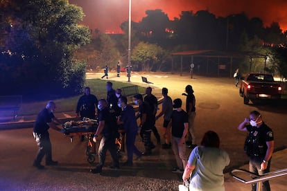Personal sanitario y policía evacúan a un paciente de un hospital infantil de Penteli, este lunes.