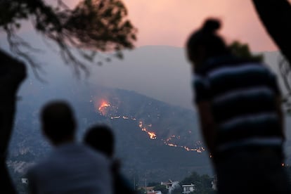 Vecinos de Penteli observan las llamas acercándose a las viviendas, este lunes.