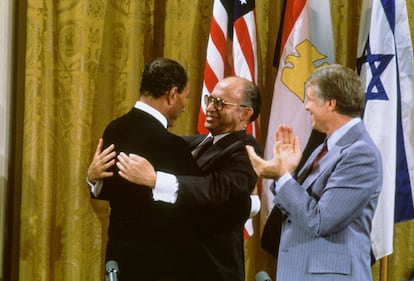 Egyptian President Anwar al-Sadat and Israeli Premier Menachem Begin embrace, while US President Jimmy Carter applauds after signing the Camp David Accords in the East Room of the White House