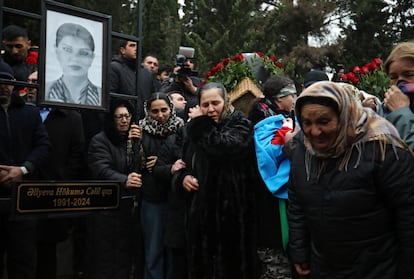 Un grupo de personas llora ante la tumba de la azafata Hokuma Aliyeva durante el funeral de los miembros de la tripulación del vuelo J2-8243 de Azerbaijan Airlines que se estrelló cerca de la ciudad kazaja de Aktau, en Bakú, Azerbaiyán, 29 de diciembre de 2024.