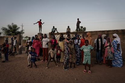 Mujeres y niños junto al muro del colegio de Colibantang, en la región senegalesa de Tambacounda, que fue construido con el dinero enviado por los emigrantes.