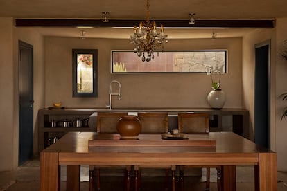 Una mesa de madera diseñada por el modelo preside un amplio comedor integrado en la cocina.