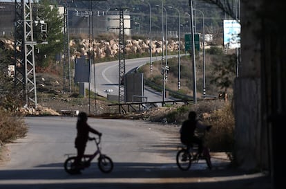 Dos niños observan la carretera que lleva al asentamiento israelí de Ateret, por donde tienen prohibido circular los palestinos, en diciembre de 2023.