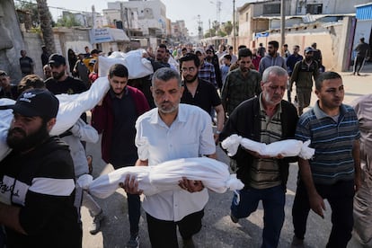 Hombres palestinos llevan los cadáveres de sus familiares muertos por un bombardeo israelí, incluidos varios niños, este miércoles en Deir al-Balah (Gaza).