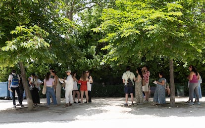 Un grupo de asistentes a la Feria del Libro de Madrid se resguardan del sol bajo la sombra de los árboles, este sábado