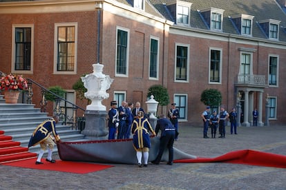 Varios trabajadores intentan colocar la alfombra roja de los invitados a la cena de trabajo ofrecida por los monarcas neerlandeses en el marco de la Cumbre de la OTAN, este martes en el Palacio Huis ten Bosch de La Haya.