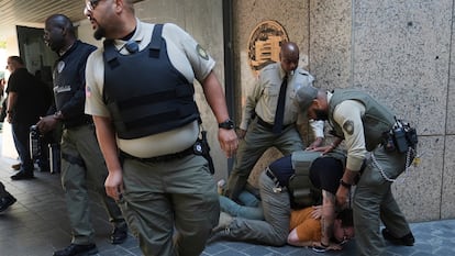 Las fuerzas del orden detienen a un manifestante en la Oficina Federal de Prisiones del Departamento de Justicia de EE. UU. tras un operativo.