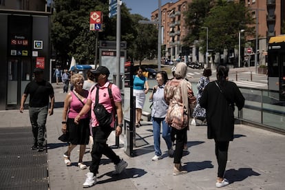 Vecinos delante de la estación del Metro del barrio de Fondo de Santa Coloma de Gramenet (Barcelona).