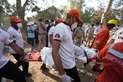 Rescatistas utilizan una camilla para retirar a una víctima del lugar de un accidente aéreo en Ahmedabad, este jueves.