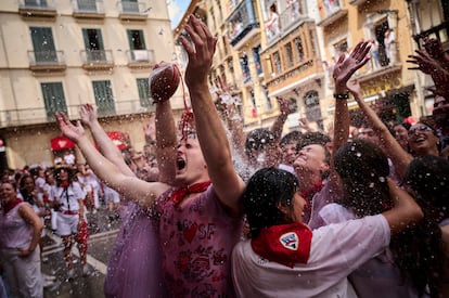 Un grupo de jóvenes se refrescan con los cubos de agua lanzados desde los balcones, este domingo en Pamplona.